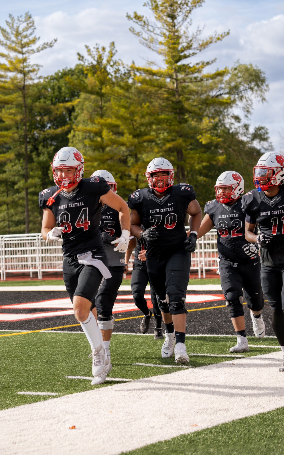 Ahren Becker running onto the field with his North Central College football teammates